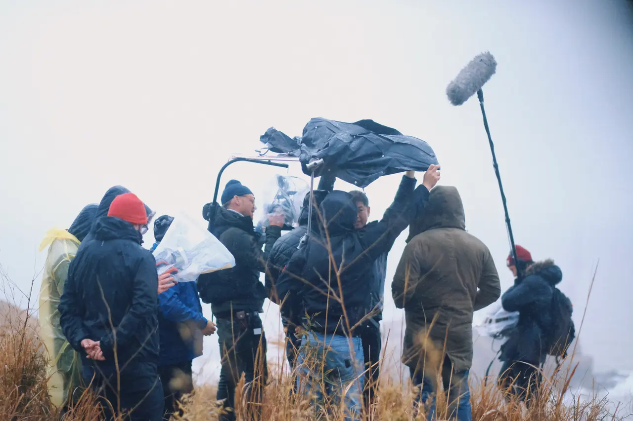 Crew filming on a windy coast